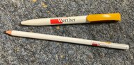 Kugelschreiber und Bleistift mit dem Logo sind zu sehen.